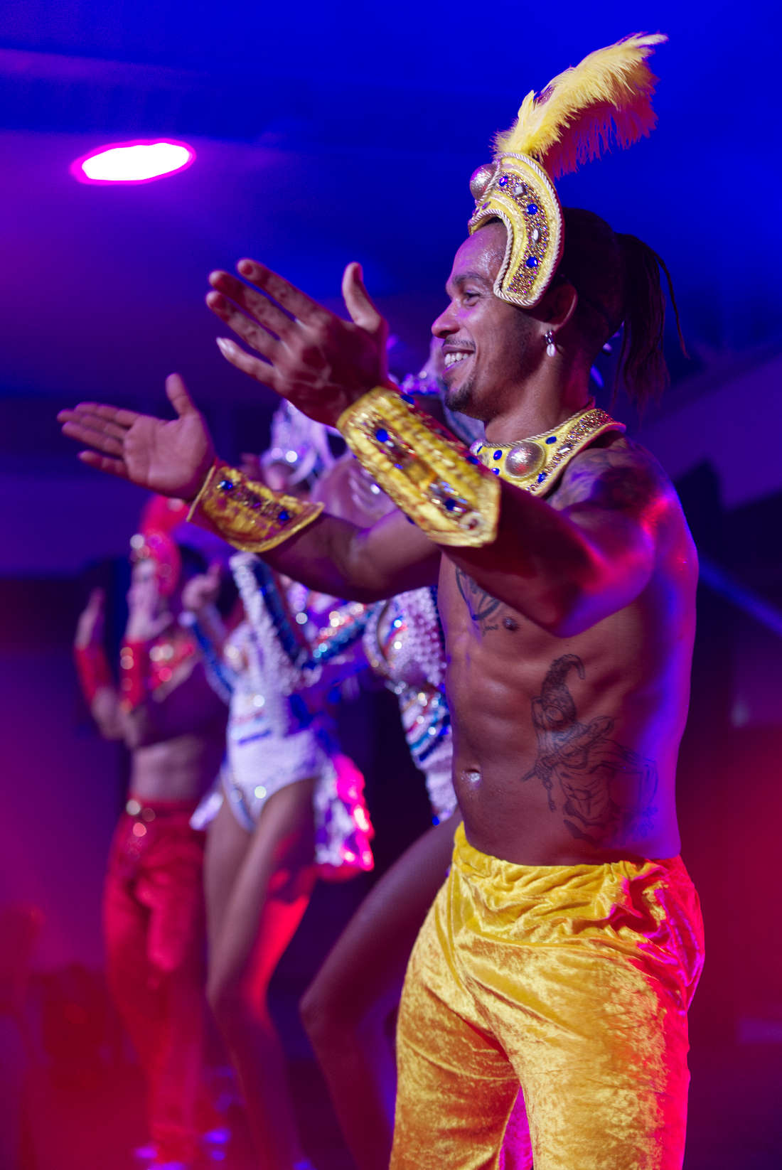 Danseur en costume de carnaval coloré, lumière de scène violette