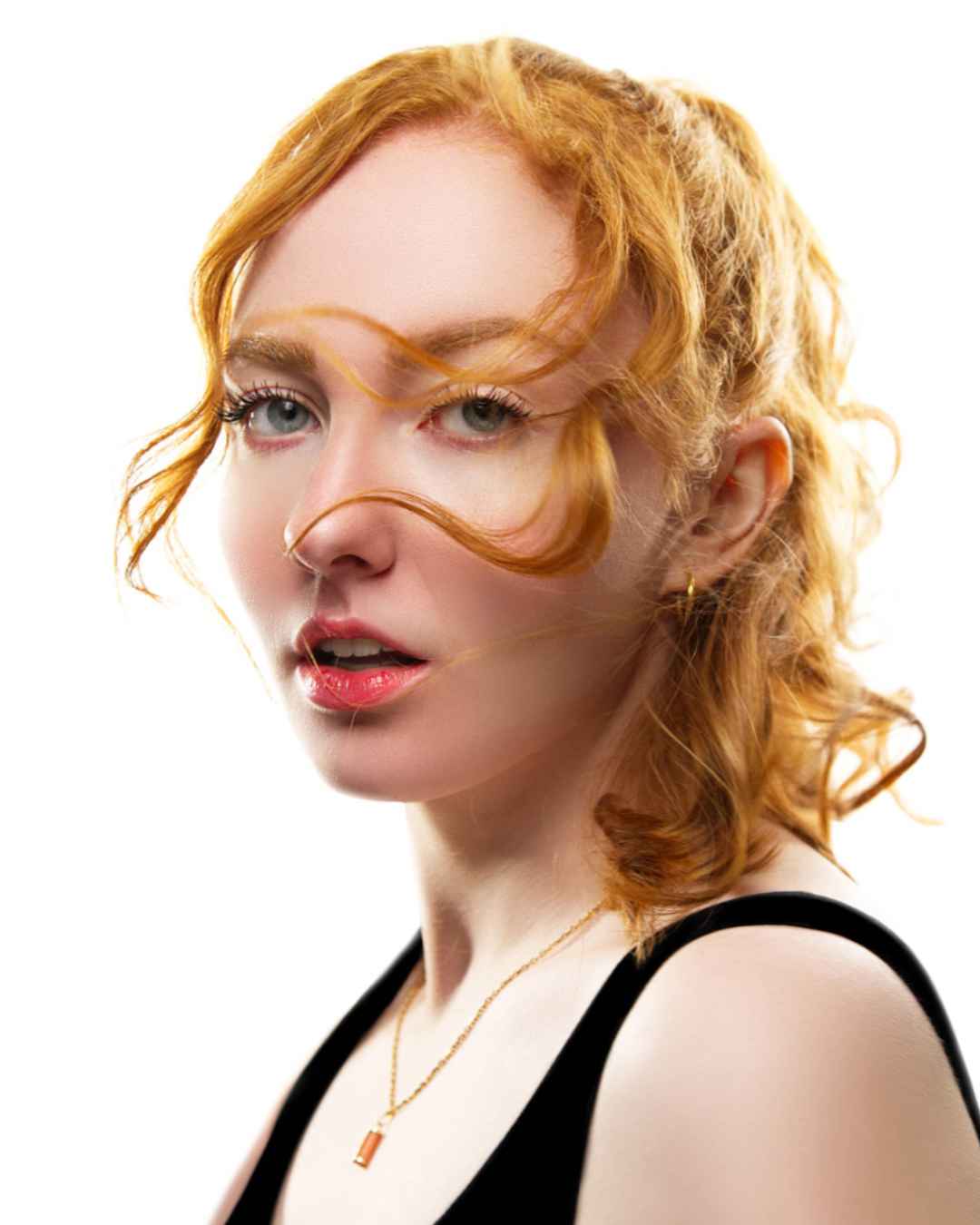 Portrait d'une femme rousse, épaule dénudée et mèche au vent