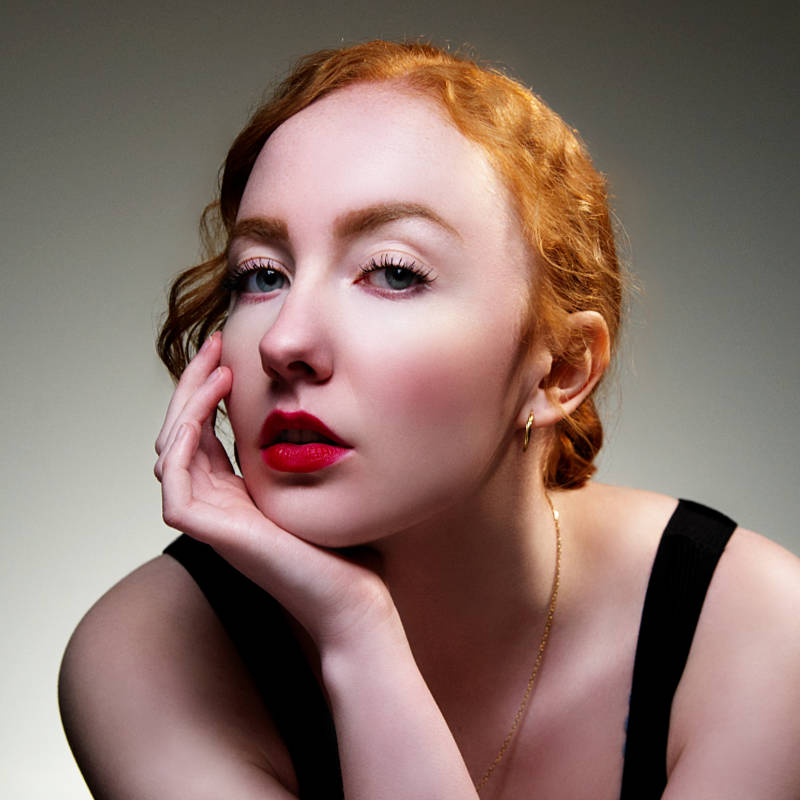Portrait d'une femme rousse, main sous le menton et rouge à lèvres
